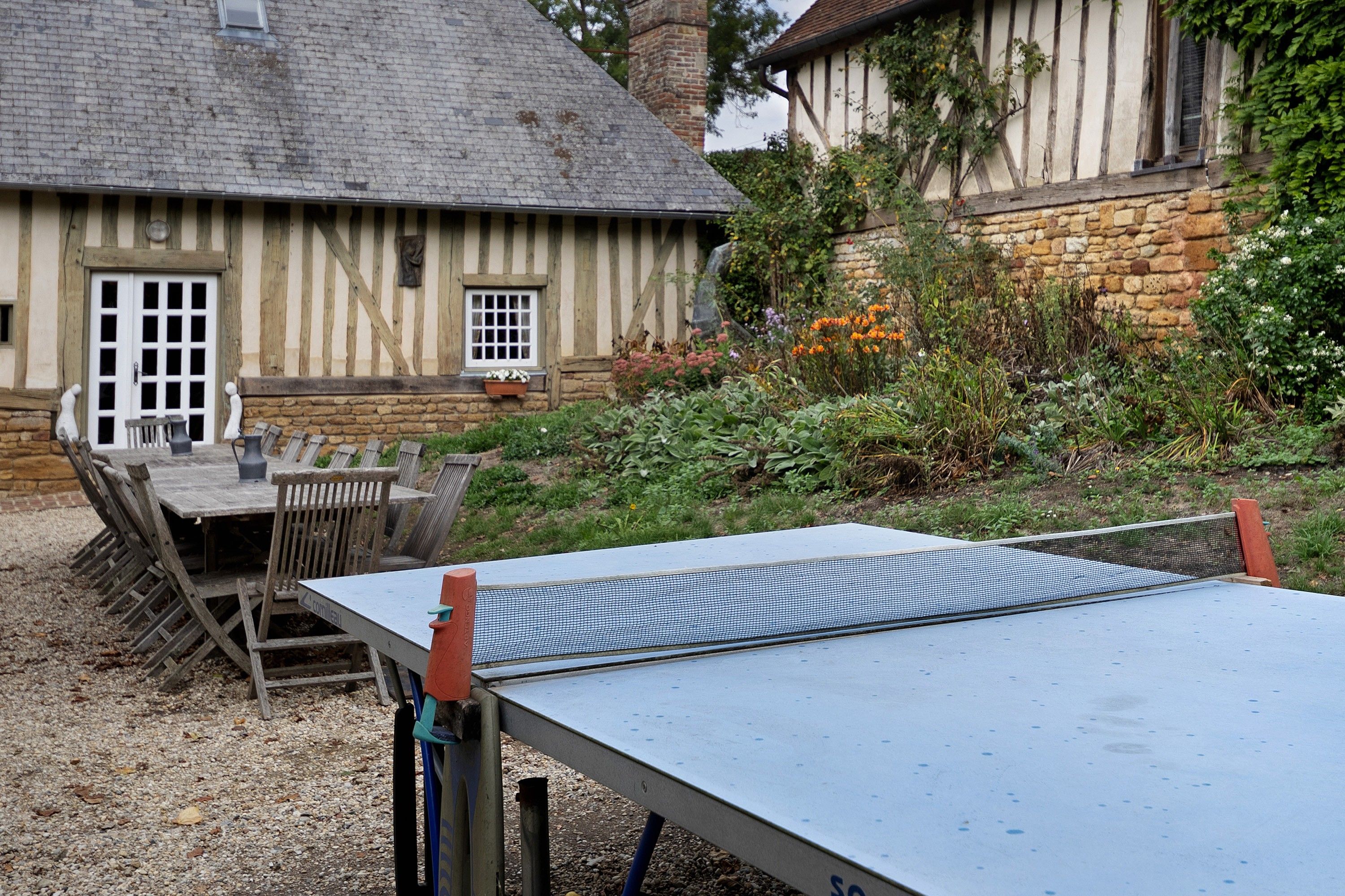Een klassiek vakwerkhuis met een stenen muur en een tuin met een tafeltennistafel.