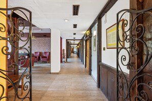 A corridor with wooden flooring, metal decorative gates, and a brick wall.