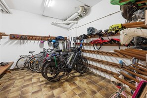 A bicycle storage area with multiple bikes and helmets.
