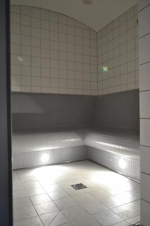 A tiled bathroom with a corner shower, a drain, and a light fixture. - Depandance Vodoléčba (Lázně Libverda)