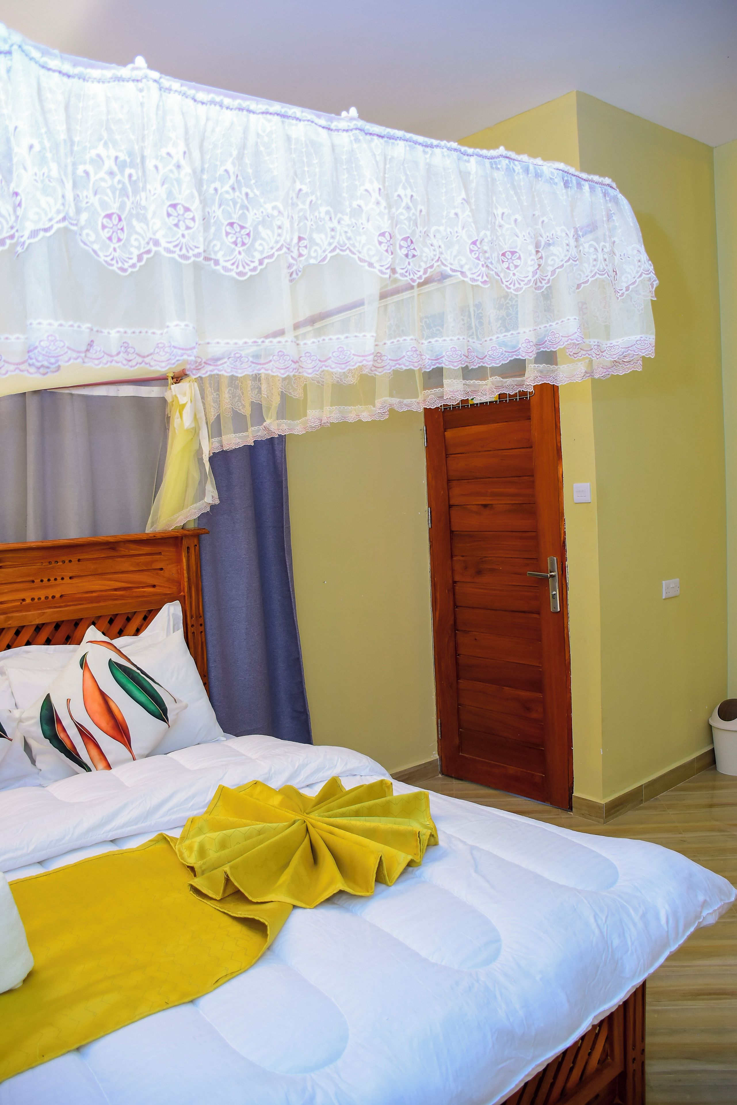 Una habitación de hotel con una cama, una puerta de madera y una ventana con cortinas.