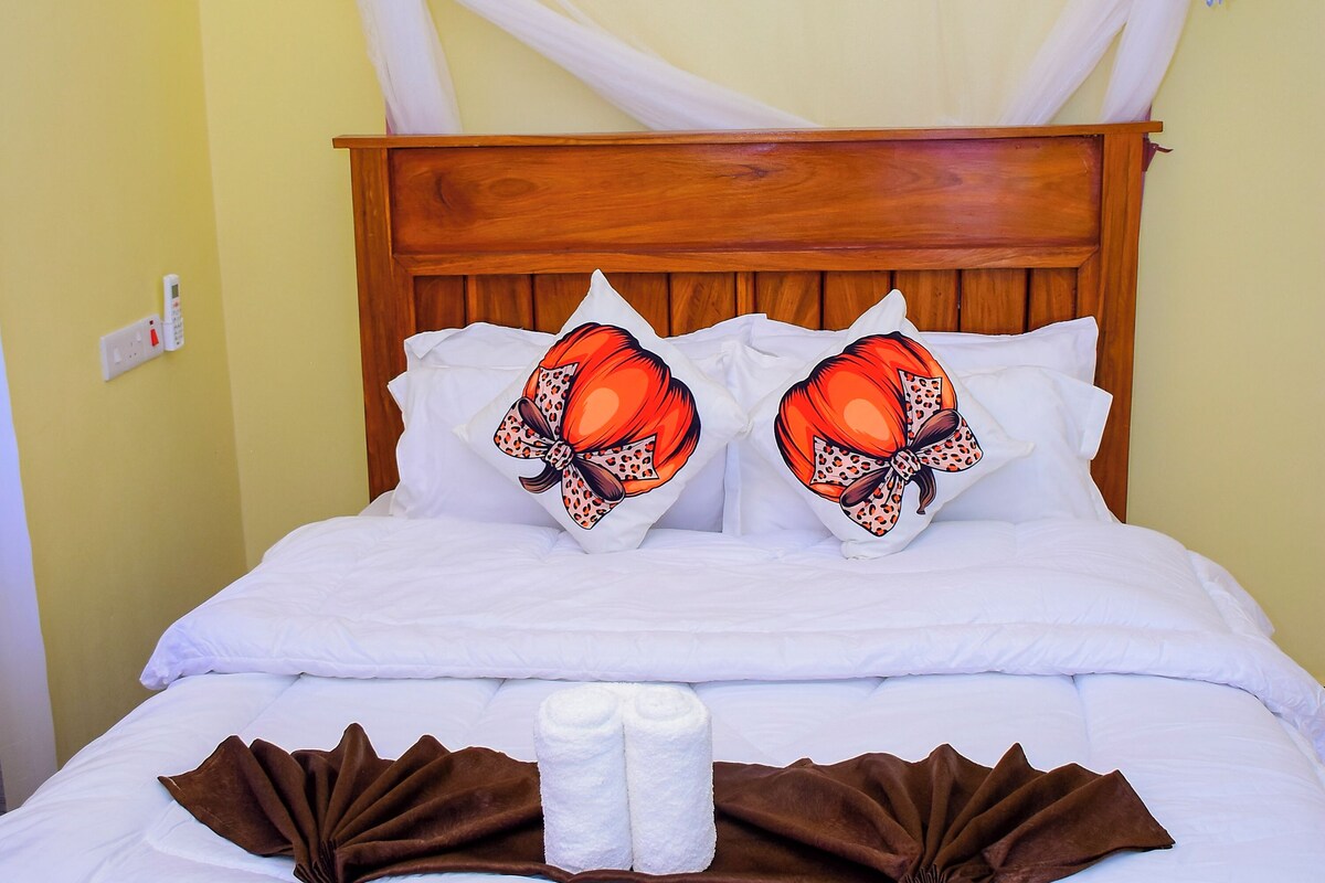 A bed with a wooden headboard, white bedding, and two decorative pillows with a bow design.