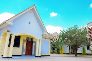 A building with a distinct architectural style, featuring a pitched roof and a central entrance with a wooden door. - SOLOMON VILLAGE LODGE DODOMA (Dodoma)