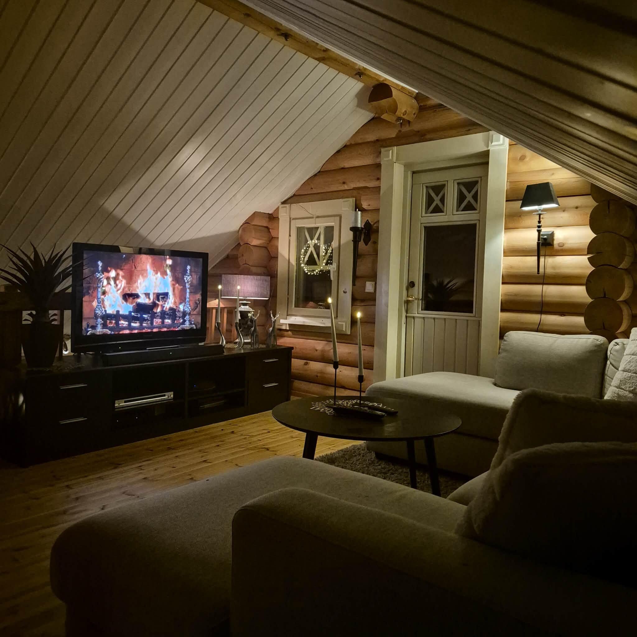 Ein gemütliches Blockhaus-Interieur mit Fernseher, Sofa und einem kleinen Tisch.