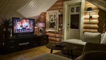 Ein gemütliches Blockhaus-Interieur mit Fernseher, Sofa und einem kleinen Tisch.