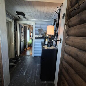 A hallway with a wooden door, a black console table with a lamp, and a heart-shaped wall decoration.