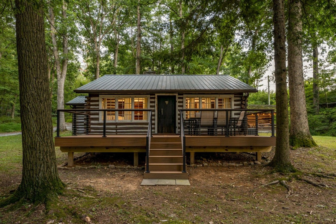 A cabin with a deck, a staircase, and a porch area.