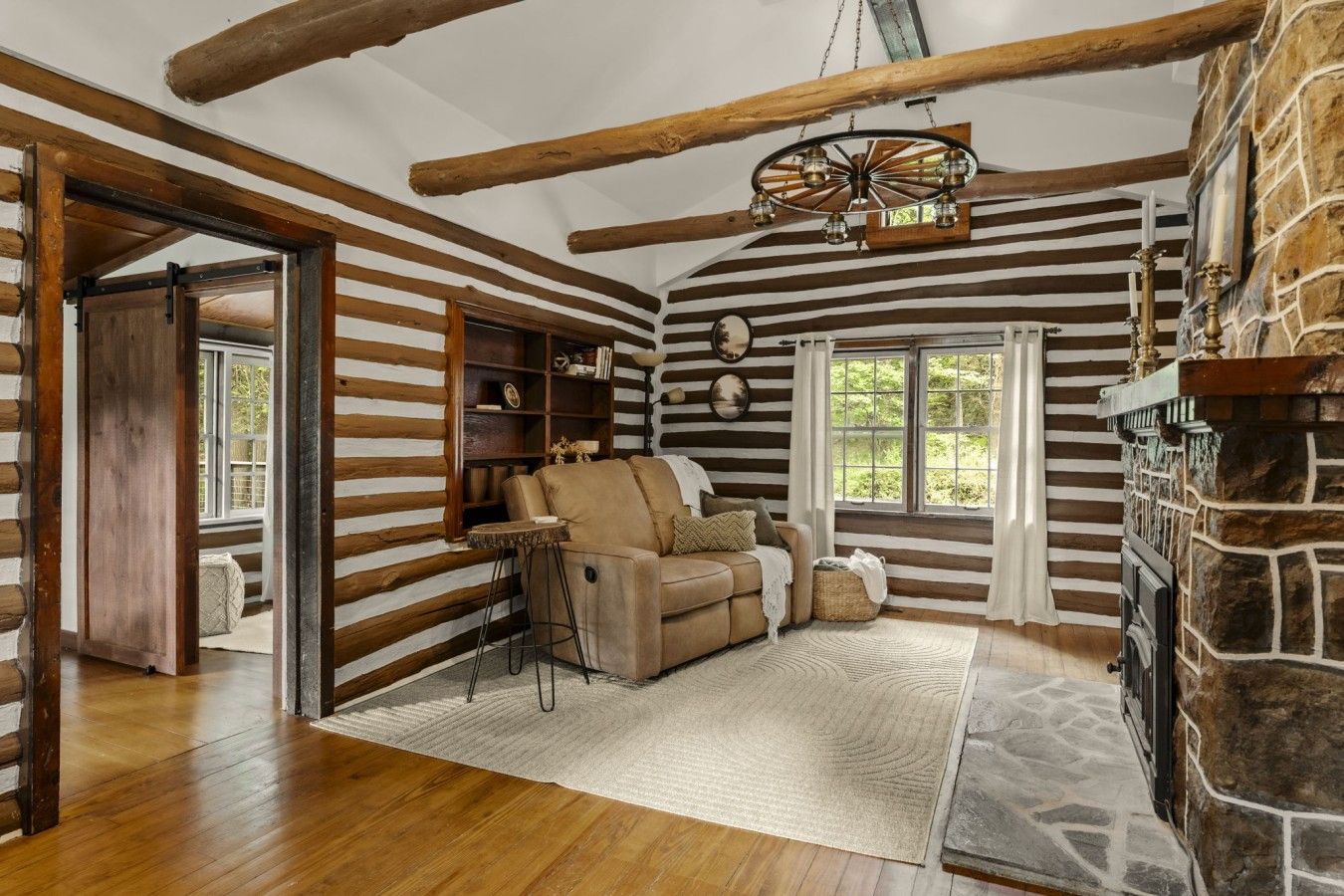 A log cabin interior with a fireplace, a sofa, and a wooden ceiling.