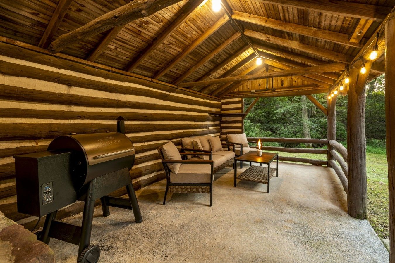 A log cabin with a barbecue grill, seating area, and a view of the outdoors.
