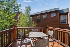 A wooden deck with a table and chairs, surrounded by a wooden railing. - Dillon 3BR Mountain Townhome | Hot Tub, Sauna, and near Breck, Keystone (Dillon)