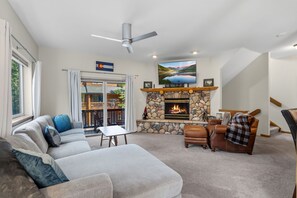 Un salon avec une cheminée, un canapé, un téléviseur et un ventilateur de plafond.