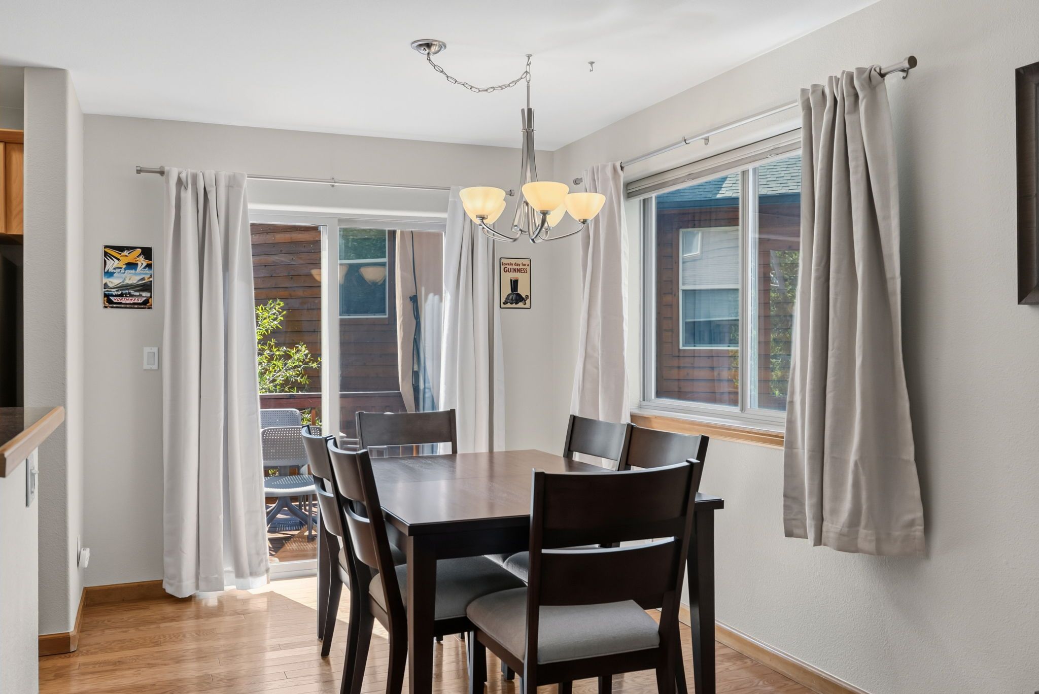Un espace repas comprenant une table et des chaises, un lustre et des rideaux.