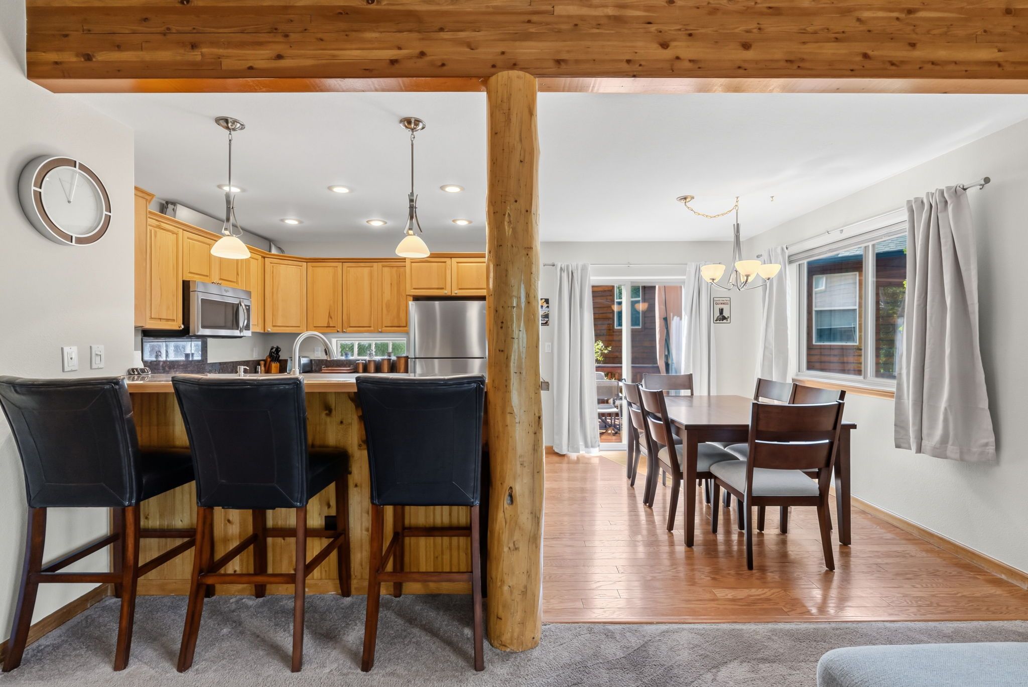A modern kitchen with wooden cabinets, stainless steel appliances, and pendant lighting.