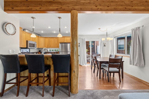 Une cuisine moderne avec des meubles en bois, des appareils électroménagers en acier inoxydable et des luminaires suspendus.