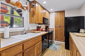 A kitchen with wooden cabinets, a black refrigerator, a microwave, and a stove. - New! Mountain Condo | Fireplace | Shared Hot Tub | 1 Mile to Purgatory Resort (Durango)