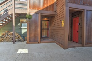 A wooden building with a red door, a metal gate, and a stack of firewood. - New! Mountain Condo | Fireplace | Shared Hot Tub | 1 Mile to Purgatory Resort (Durango)