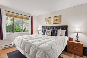 A bedroom with a large bed, two bedside tables, a window with curtains, and two framed pictures on the wall. - New! Mountain Condo | Fireplace | Shared Hot Tub | 1 Mile to Purgatory Resort (Durango)