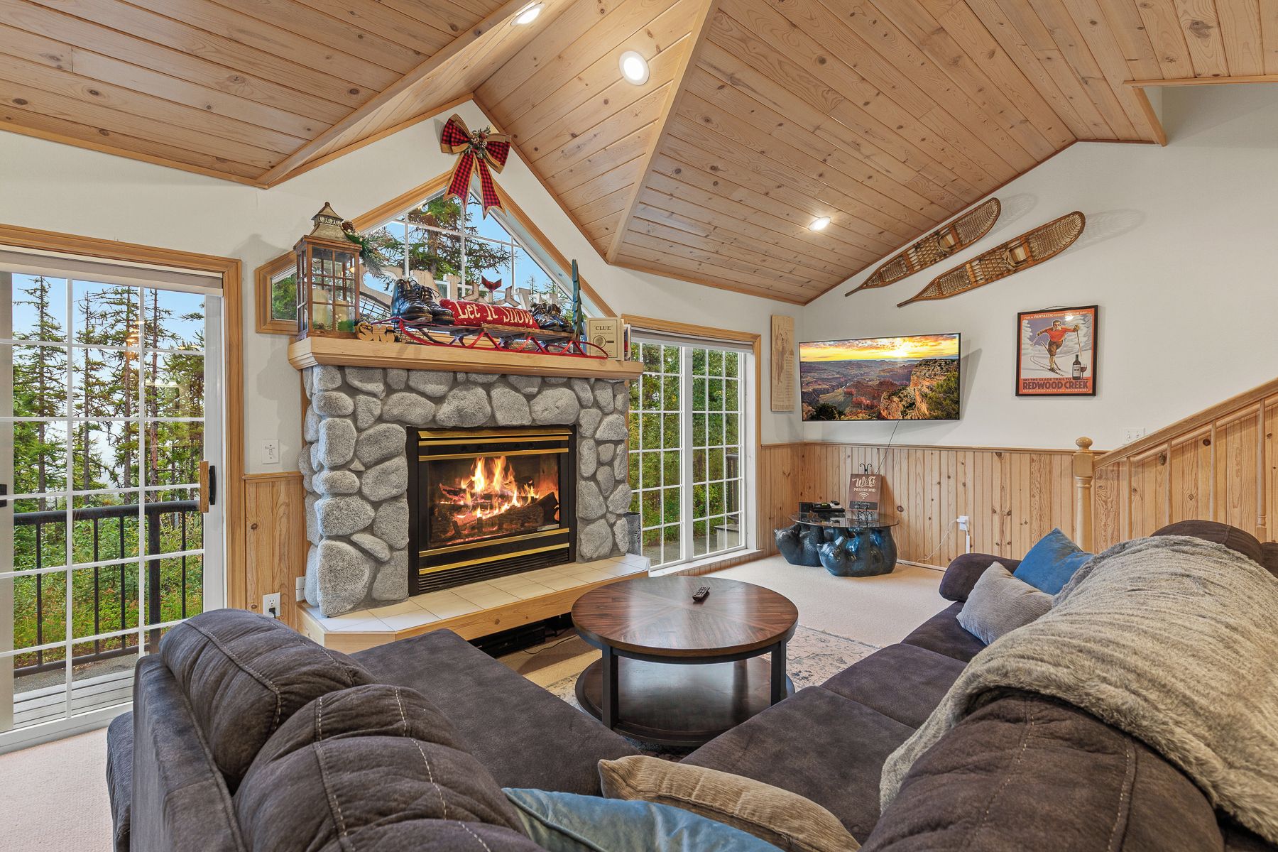 Living room with large stone fireplace, comfortable couch and Smart TV.