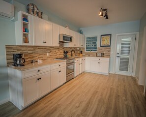 A modern kitchen with white cabinets, a wooden backsplash, and a built-in oven. - Modern Luxury Escape (Jolly Harbour)