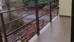 Ein Balkon mit Metallgeländer, der auf Gleise und Palmen blickt.