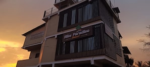 A multi-story building with a sign for 'Bliss Paradise Resort.' - Bliss paradise resort (Malvan)