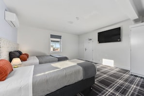 A hotel room with two beds, a television, a window, and a door.