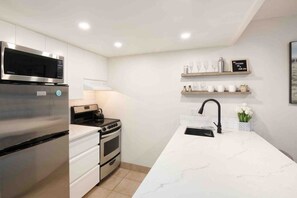 Una cocina moderna con electrodomésticos de acero inoxidable, una encimera blanca y un horno empotrado.