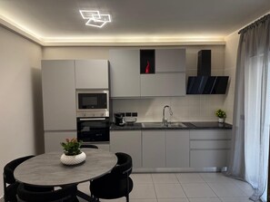 Une cuisine moderne équipée d’un four encastré, d’un four à micro-ondes, d’un évier et d’un coin repas avec une table ronde et des chaises.