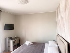 A hotel room with a bed, a desk, and a television.