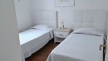 Un dormitorio con dos camas individuales, una mesita de noche, una lámpara y un cuadro enmarcado en la pared.