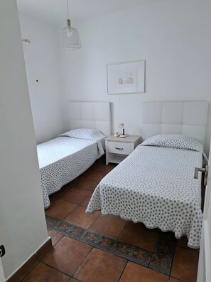 A bedroom with two single beds, a nightstand, a lamp, and a framed picture on the wall.
