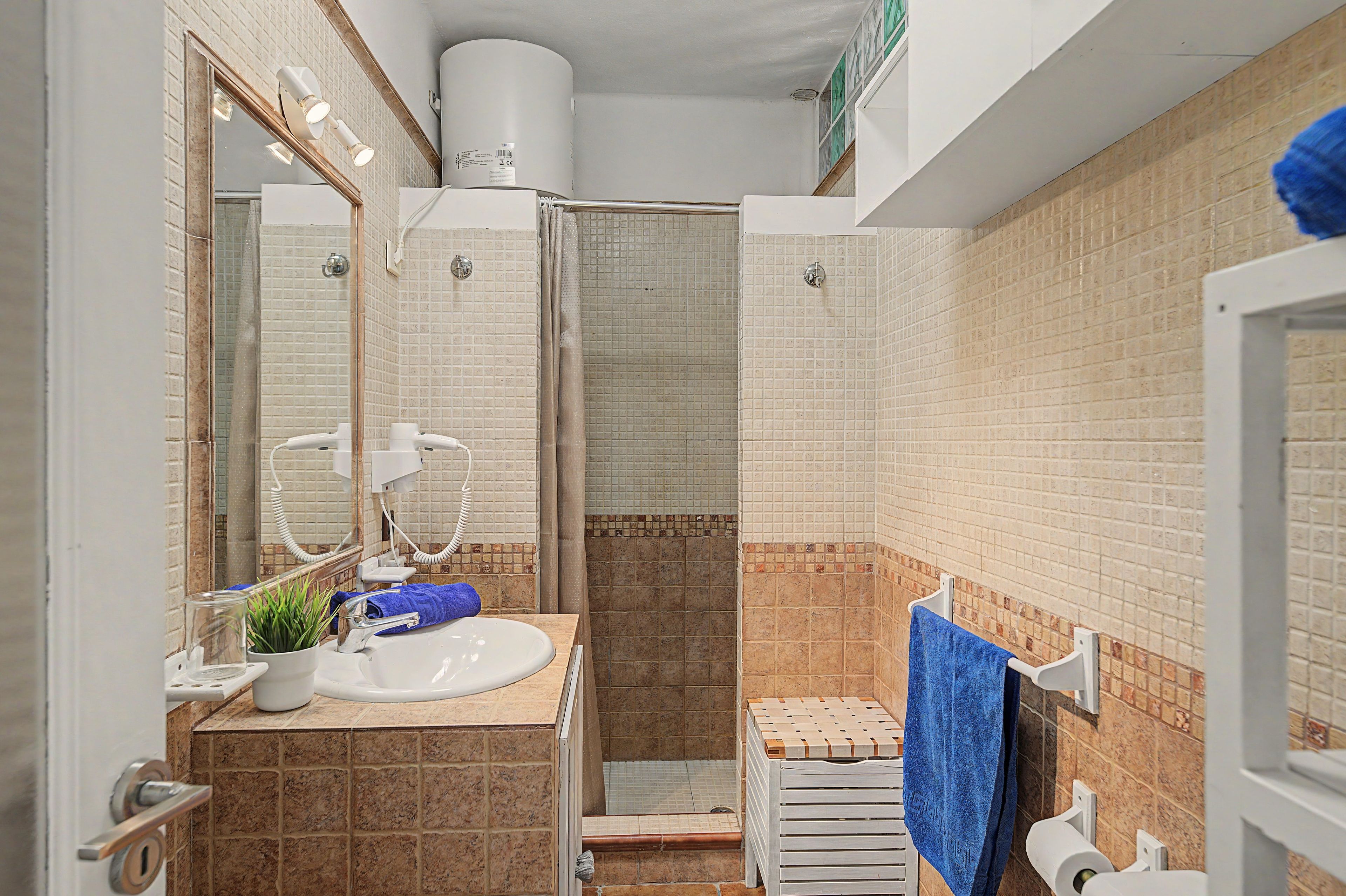 Een badkamer met een wastafel, spiegel, handdoekhouder en douche.
