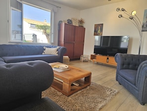 A living room with a sofa, a coffee table, a television, and a cabinet.
