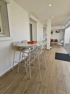 A modern interior with a dining area featuring a round table and chairs, a kitchen area with a stove and cabinets, and a balcony with a view. - Villa Victoria 5*, Oceanfront, Pool, Air Conditioning, Renovated Home, New Amenities (L'Aiguillon-la-Presqu'île)