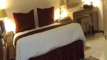 Ein Hotelzimmer mit einem Bett, Nachttischlampen, einem Schminktisch, einem Spiegel und einem Teppich.