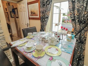 A dining table set with various dishes, glasses, and cutlery, with a window view and curtains in the background. - BRUCKLESS REST FINE COUNTRY LIVING B&B in Bruckless, County Donegal (Bruckless)