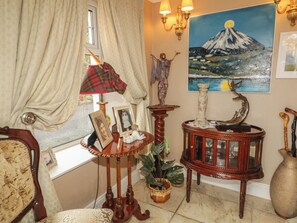 A room with a window, a painting of a mountain, a lamp, and a table with a plant. - BRUCKLESS REST FINE COUNTRY LIVING B&B in Bruckless, County Donegal (Bruckless)