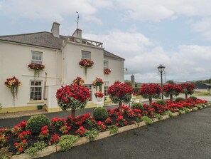 A white building with multiple flower boxes on the windowsills, a paved driveway, and a clear sky. - BRUCKLESS REST FINE COUNTRY LIVING B&B in Bruckless, County Donegal (Bruckless)