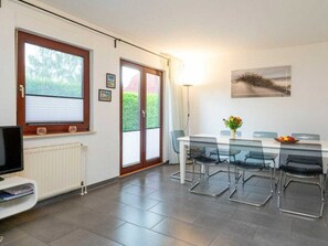 Eine moderne Küche mit Essbereich, ausgestattet mit einem großen Fenster, einem Flachbildfernseher und einem Tisch mit Stühlen.