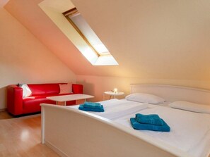Ein Schlafzimmer mit einem Bett, einem roten Sofa, einem kleinen Tisch und einem Nachttisch.