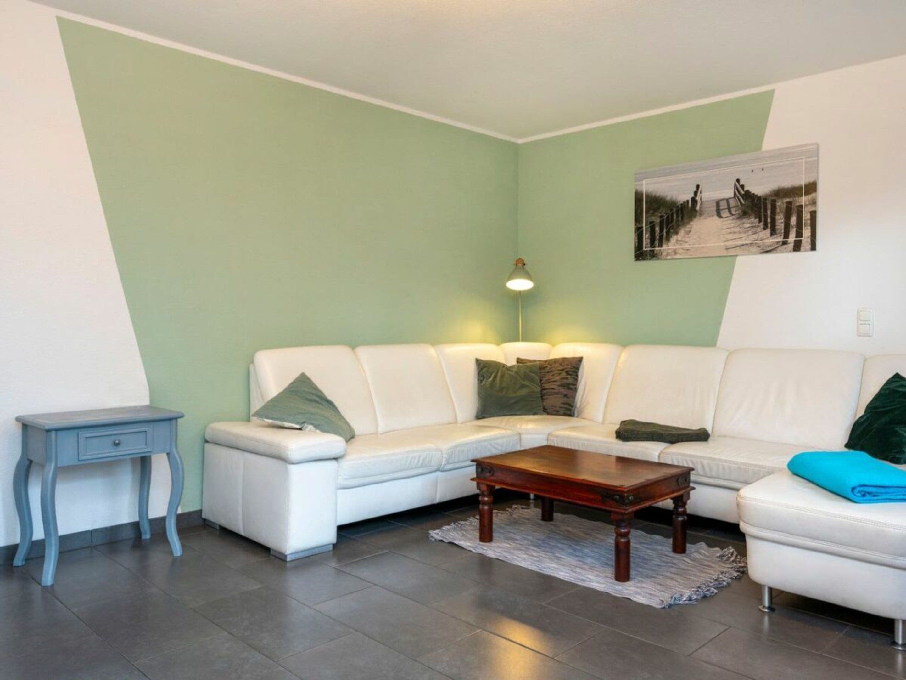 Una sala de estar con un sofá blanco, una mesa de centro de madera y una mesita auxiliar.