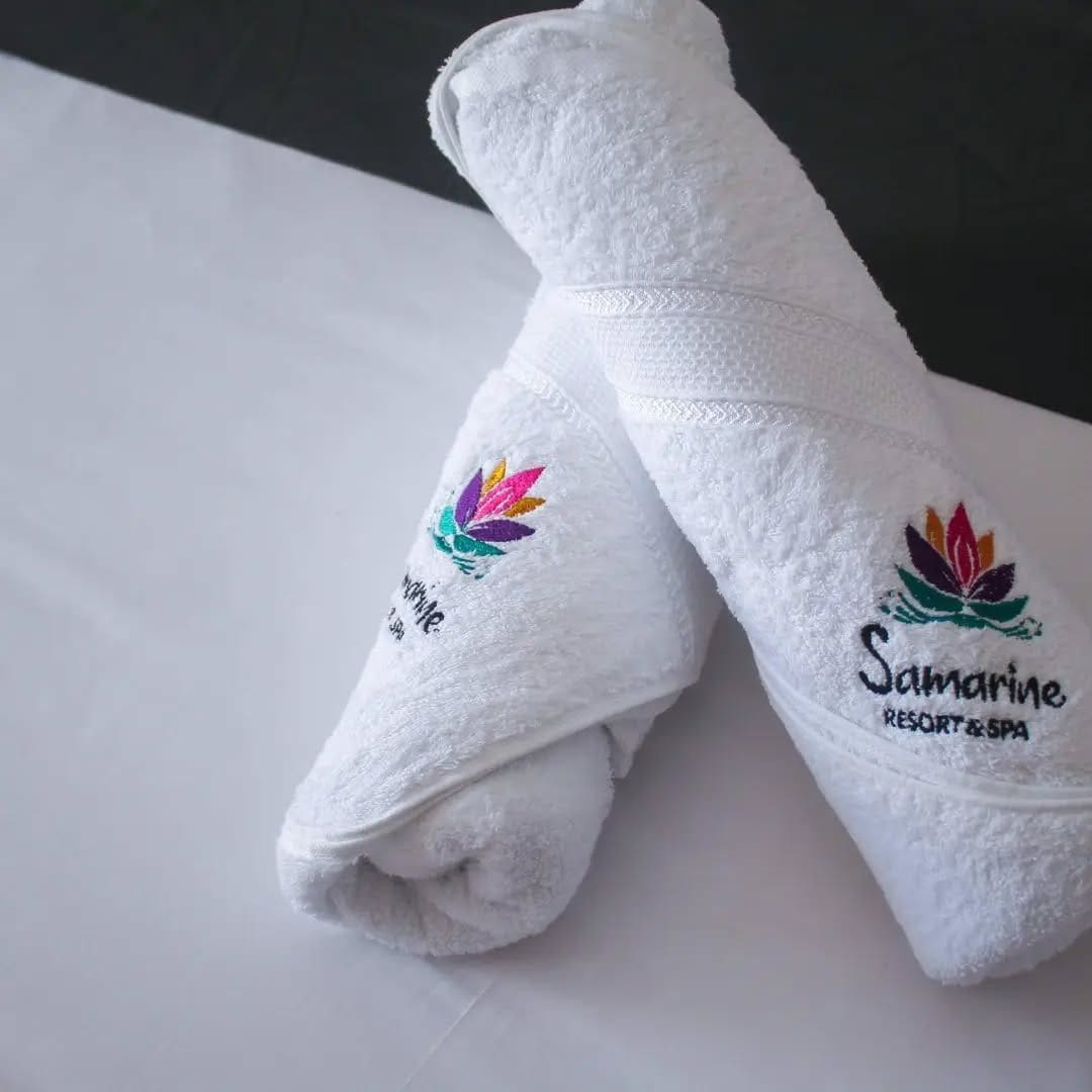 Two white towels with embroidered logos and text, placed on a flat surface.
