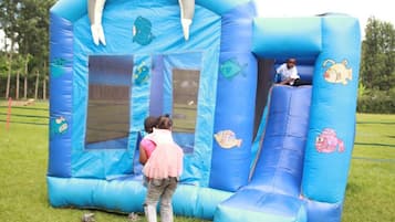 A blue inflatable play structure with slides and a climbing wall, designed for children.