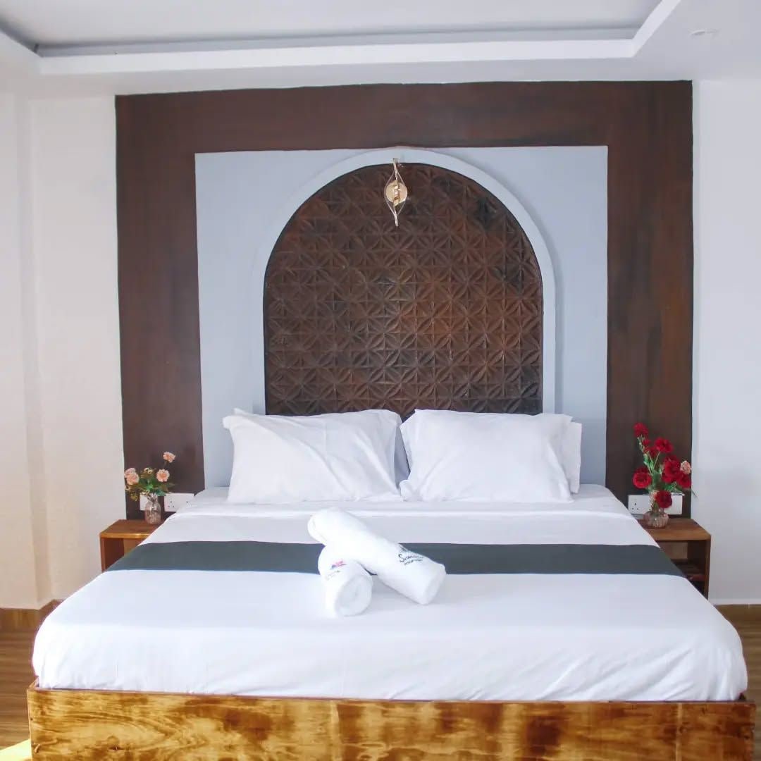 Habitación de hotel con una cama grande, cabecera de madera y un panel decorativo en la pared.