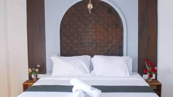 Habitación de hotel con una cama grande, cabecera de madera y un panel decorativo en la pared.