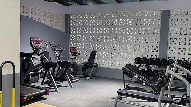 A gym with exercise equipment, a wall with patterned design, and a ceiling with skylights. - Samarine Resort & Spa Maragua (Maragua)