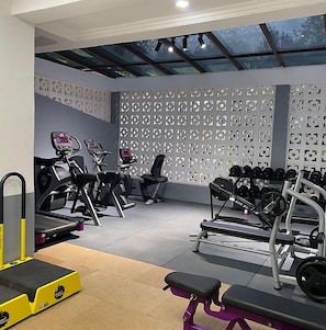 A gym with exercise equipment, a wall with patterned design, and a ceiling with skylights. - Samarine Resort & Spa Maragua (Maragua)