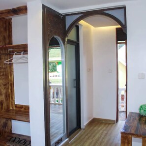 Un pasillo con un banco de madera, perchero y puerta que da al exterior.