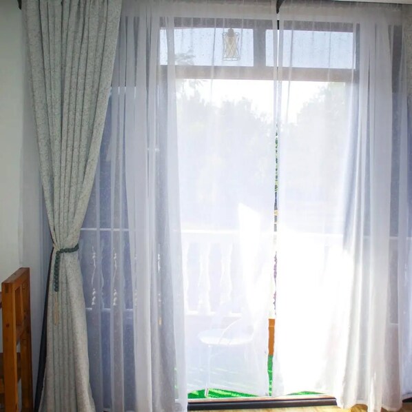 A room with a large window covered by sheer curtains, a wooden chair, and a green object on the windowsill. - Samarine Resort & Spa Maragua (Maragua)