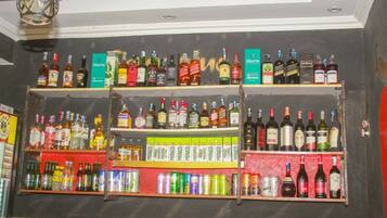 A bar with shelves stocked with various bottles and cans, including spirits and sodas.